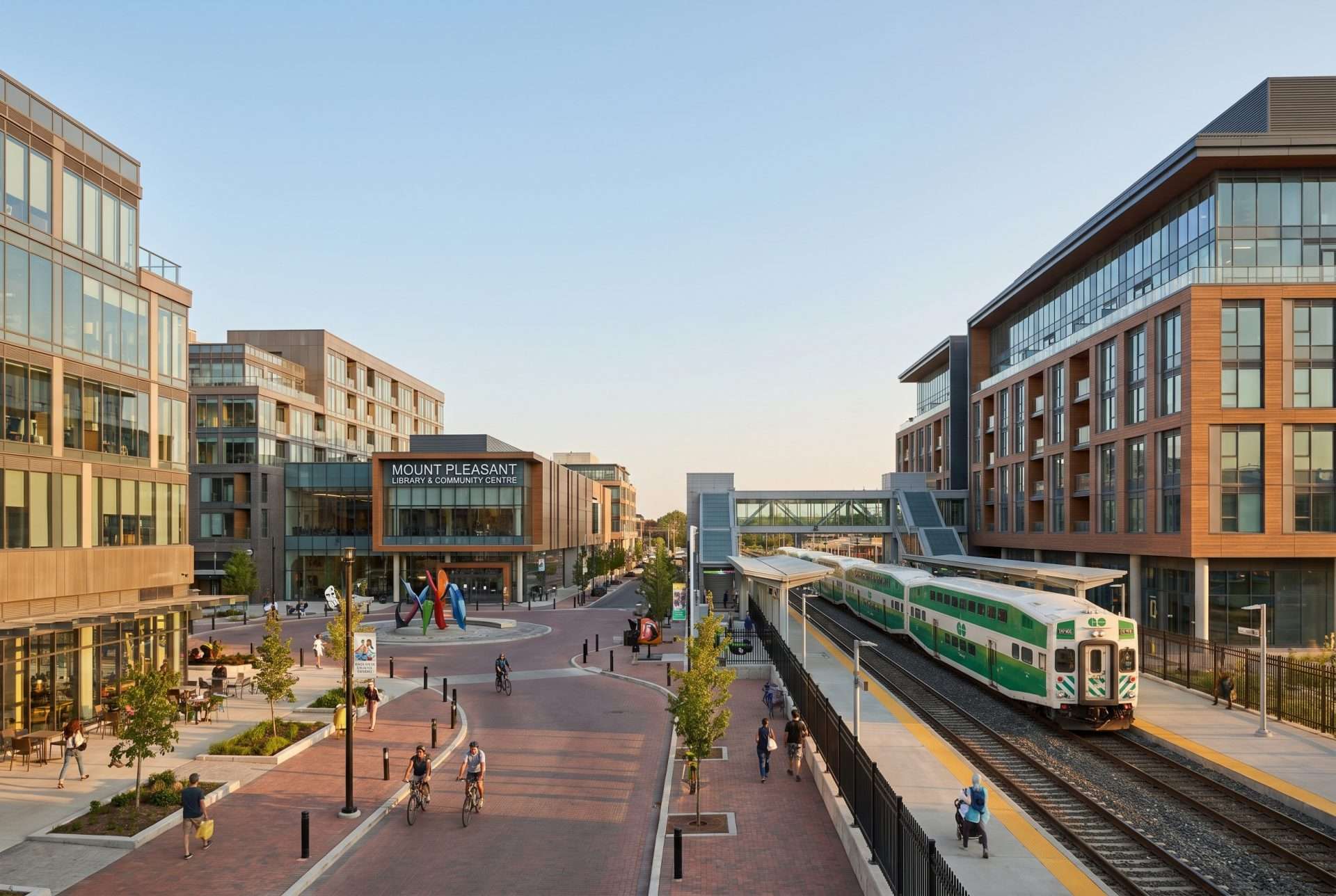 Urban Mount Pleasant street with a transit line, mid-rise buildings and pedestrians.
