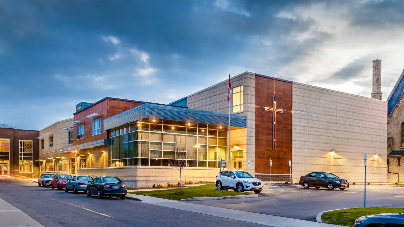 Catholic School in Brampton | Schools in Brampton: A Guide for Families | Brampton Homes Modern school building with a cross on the facade and large glass entrance under a cloudy evening sky.